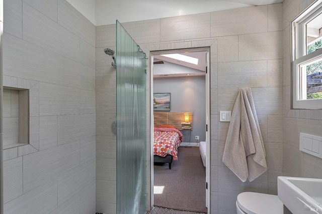 ensuite bathroom with tiled shower, toilet, plenty of natural light, and a sink