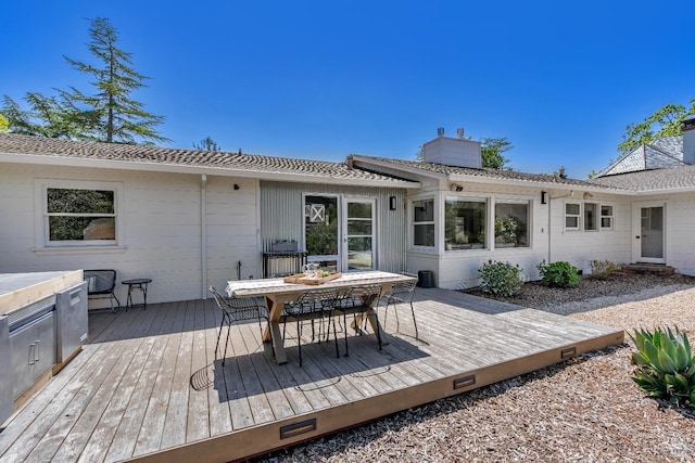 back of house featuring a chimney, outdoor dining space, and a wooden deck