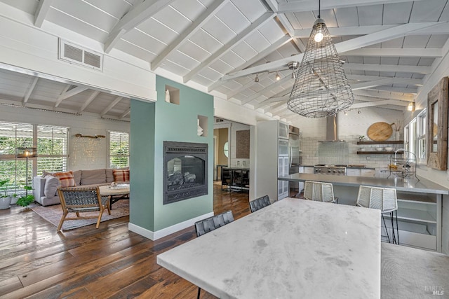 kitchen featuring a multi sided fireplace, dark wood-style floors, a sink, wall chimney range hood, and baseboards