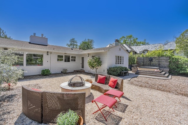 back of property with a fire pit, a chimney, and a patio