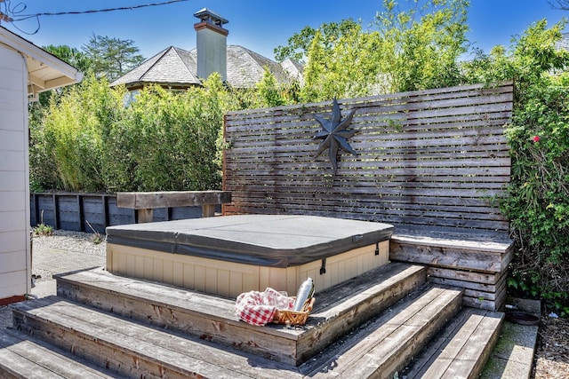 wooden terrace with a covered hot tub and fence