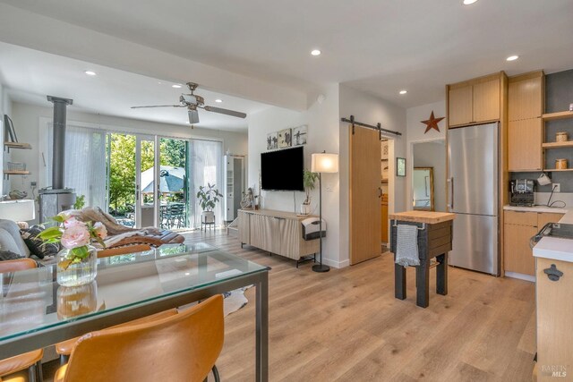 kitchen featuring stainless steel fridge, a barn door, open floor plan, open shelves, and light brown cabinets