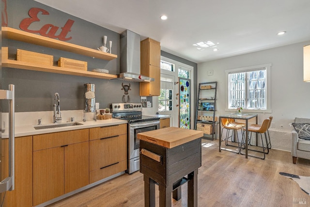 kitchen with electric range, a sink, wall chimney range hood, light wood finished floors, and recessed lighting