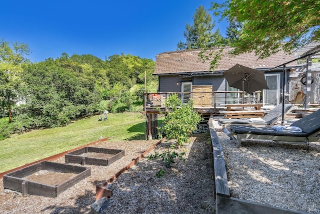 rear view of property featuring a garden, a yard, a wooden deck, and a shingled roof