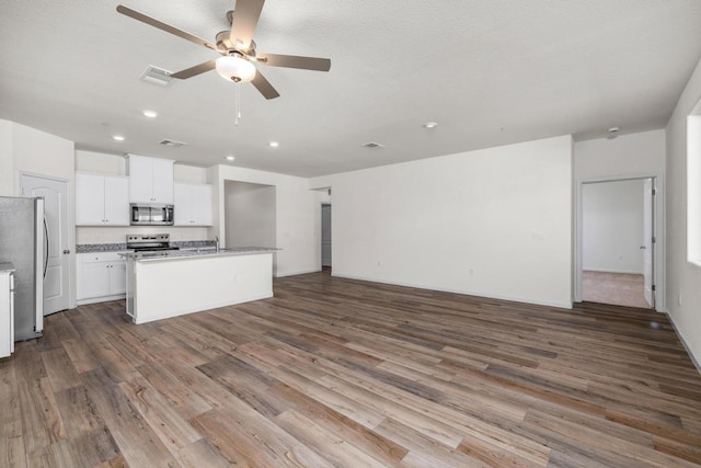 4507 Amble Ln, Riverbank, CA 95367 - kitchen with appliances with stainless steel finishes, open floor plan, ceiling fan, wood finished floors, and a center island with sink