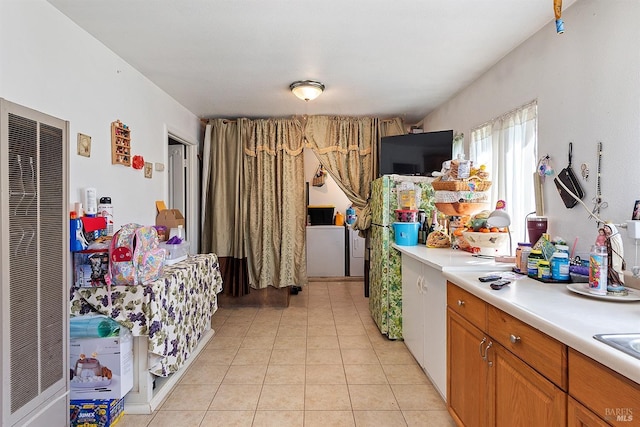 kitchen featuring brown cabinets, light tile patterned floors, light countertops, and a heating unit
