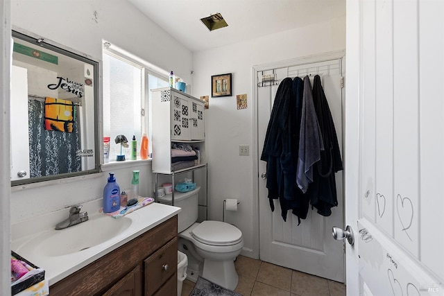 bathroom with toilet, vanity, and tile patterned flooring