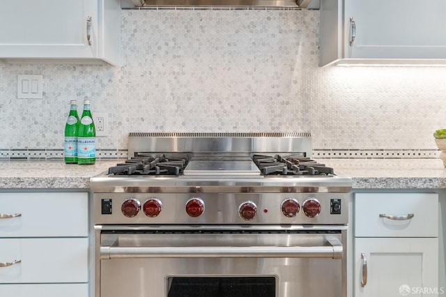 kitchen with light countertops, backsplash, white cabinets, extractor fan, and high end stainless steel range