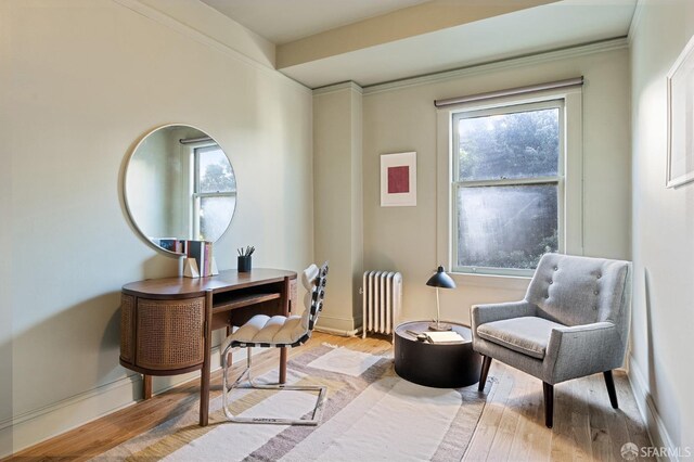 living area with radiator heating unit, light wood-type flooring, and baseboards