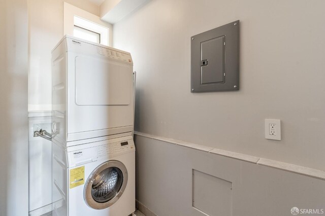 laundry room featuring stacked washer / dryer and electric panel