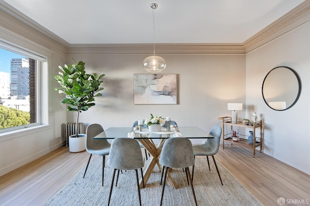 dining area featuring baseboards, light wood-type flooring, and crown molding