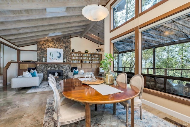 dining area featuring visible vents, baseboards, a fireplace, beam ceiling, and high vaulted ceiling