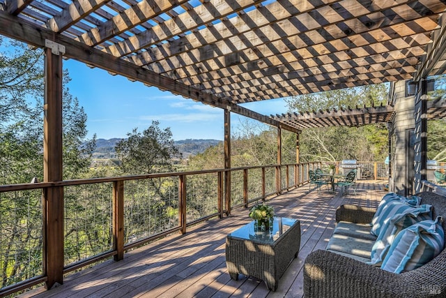 wooden terrace with a mountain view, outdoor dining space, area for grilling, and a pergola