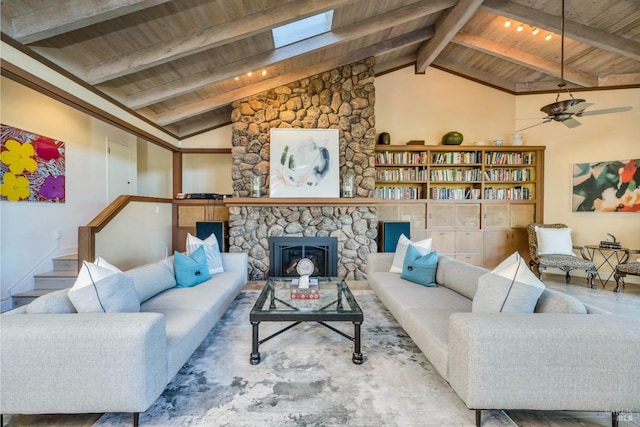 living area featuring a stone fireplace, beamed ceiling, ceiling fan, high vaulted ceiling, and wood ceiling