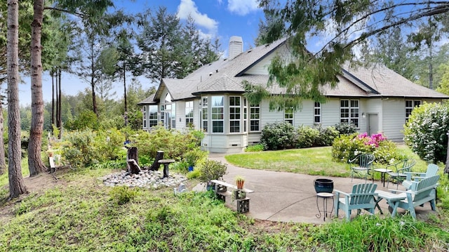 rear view of house featuring a chimney, an outdoor fire pit, a shingled roof, and a patio area