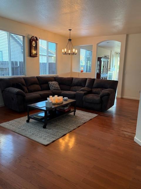 living room with baseboards, arched walkways, wood finished floors, and a textured ceiling