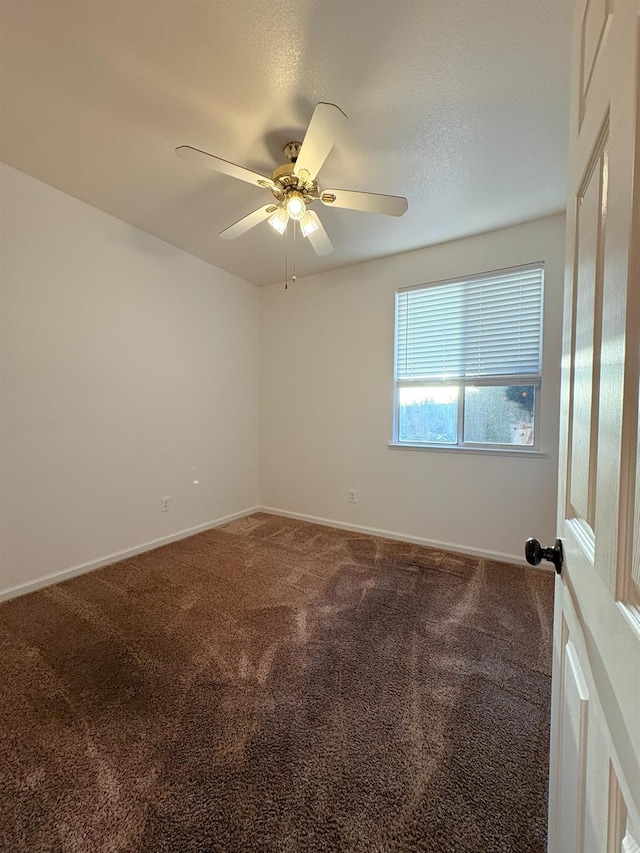 carpeted spare room featuring baseboards and ceiling fan