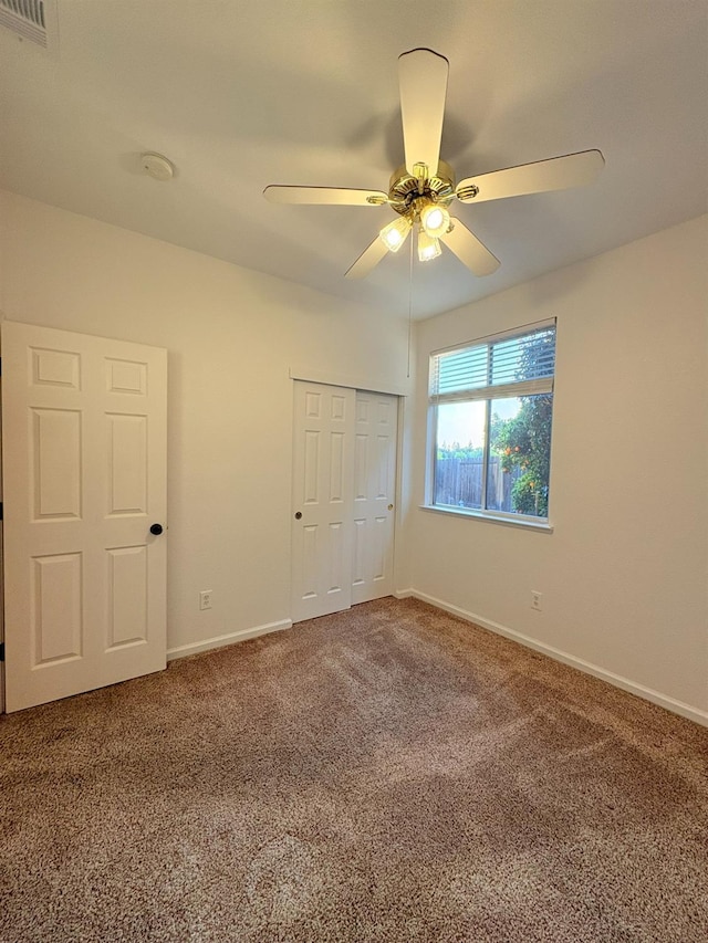 unfurnished bedroom with carpet, a closet, a ceiling fan, visible vents, and baseboards