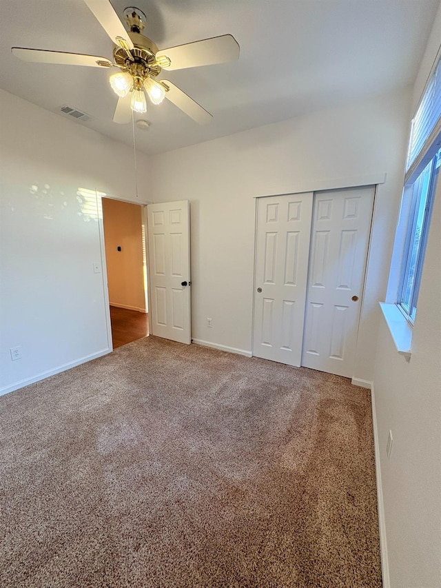 unfurnished bedroom featuring carpet, a closet, a ceiling fan, visible vents, and baseboards