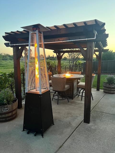 patio terrace at dusk featuring an outdoor fire pit, fence, and a pergola
