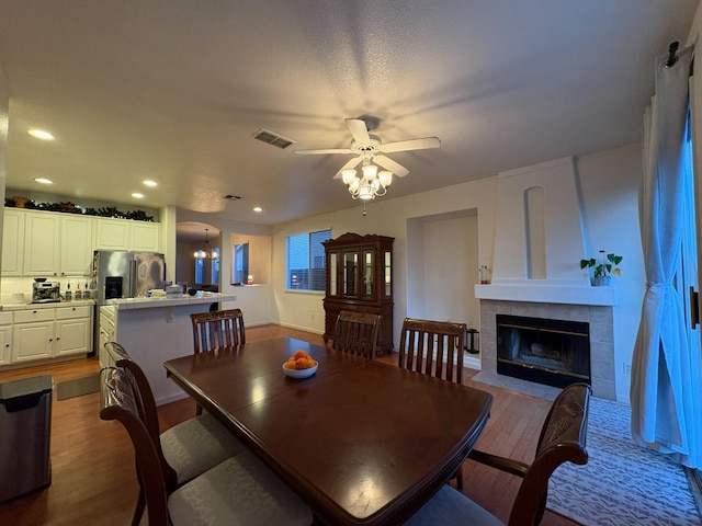 dining area with visible vents, ceiling fan, recessed lighting, wood finished floors, and a tile fireplace