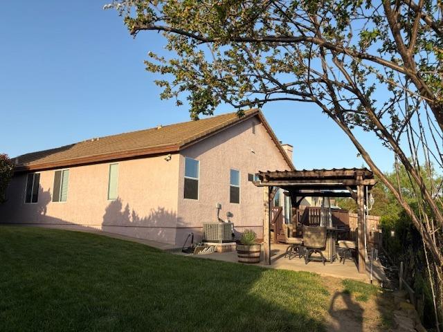 back of property with a pergola, a patio area, stucco siding, and a lawn