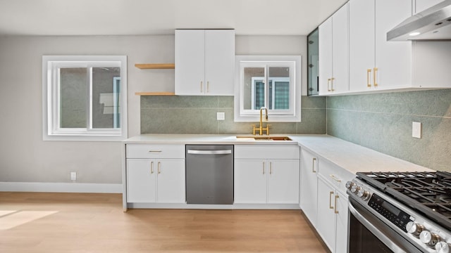 kitchen with a sink, light wood-style floors, stainless steel appliances, light countertops, and under cabinet range hood