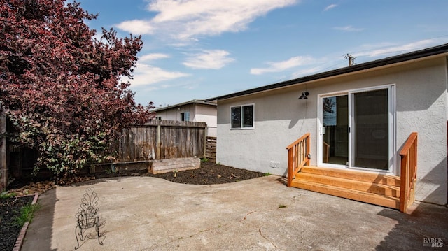 rear view of house featuring entry steps, a patio area, stucco siding, and fence