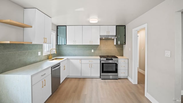 kitchen with open shelves, a sink, light wood-type flooring, appliances with stainless steel finishes, and under cabinet range hood
