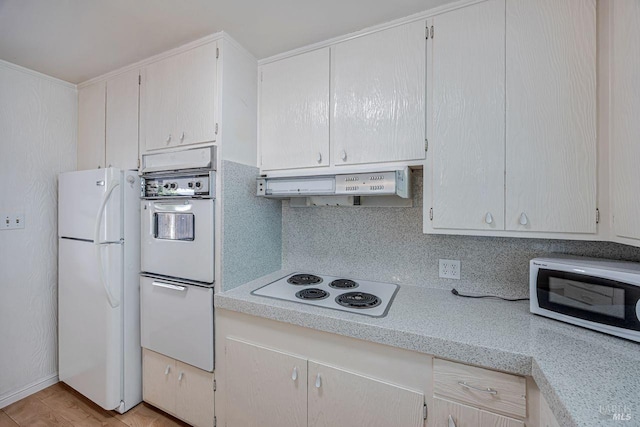 kitchen with backsplash, under cabinet range hood, and white appliances
