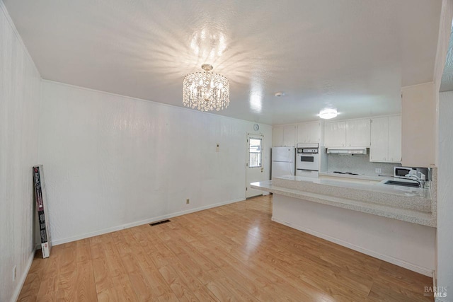 kitchen featuring light countertops, light wood-type flooring, a notable chandelier, and white appliances
