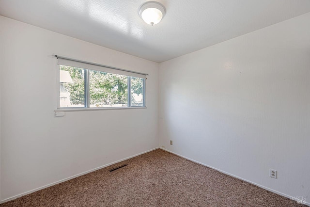 carpeted spare room featuring baseboards and visible vents