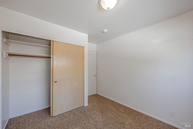 unfurnished bedroom featuring carpet floors, a closet, and baseboards