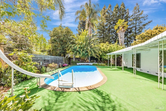 view of swimming pool with a water slide, a fenced in pool, and a fenced backyard