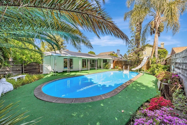 view of swimming pool with a water slide, a fenced in pool, and a fenced backyard