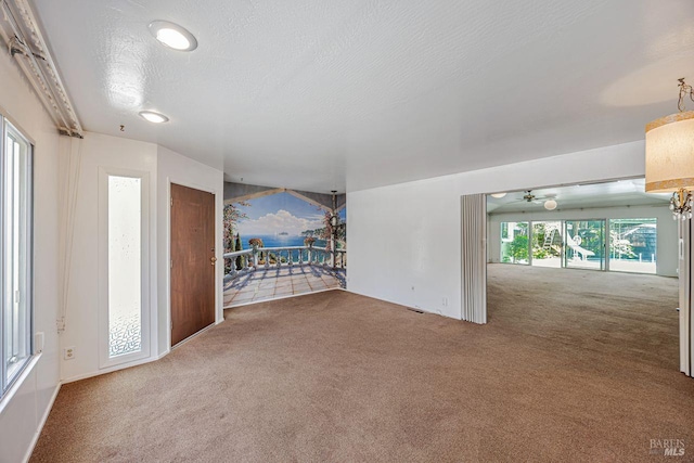 unfurnished living room featuring a ceiling fan and carpet flooring