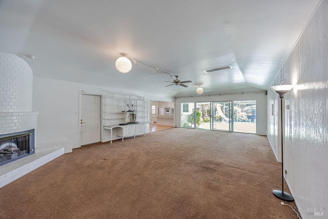 unfurnished living room with track lighting, vaulted ceiling, a ceiling fan, carpet floors, and a brick fireplace