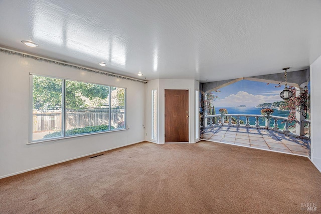 empty room featuring baseboards, a textured ceiling, visible vents, and carpet