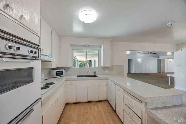 kitchen with light countertops, tasteful backsplash, a sink, and white appliances