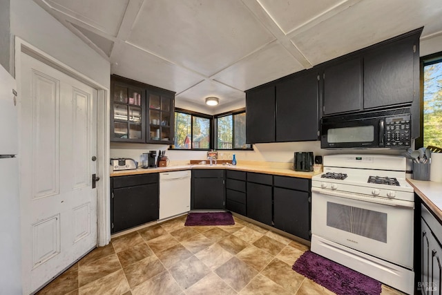 kitchen featuring a sink, light countertops, white appliances, and plenty of natural light