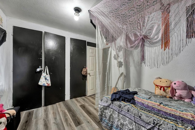 bedroom featuring a textured ceiling, multiple closets, and wood finished floors