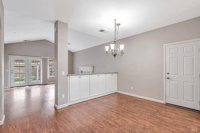unfurnished dining area featuring wood finished floors, baseboards, vaulted ceiling, and visible vents