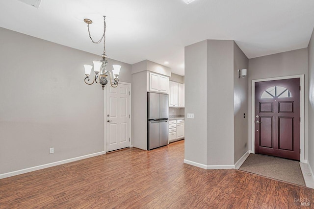 entryway with a chandelier, light wood-style flooring, and baseboards