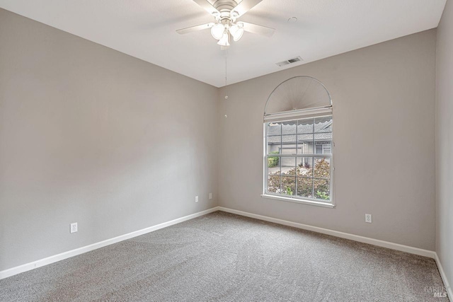carpeted spare room with ceiling fan, baseboards, and visible vents