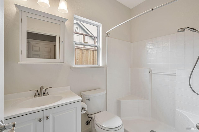 full bathroom with toilet, a tile shower, and vanity