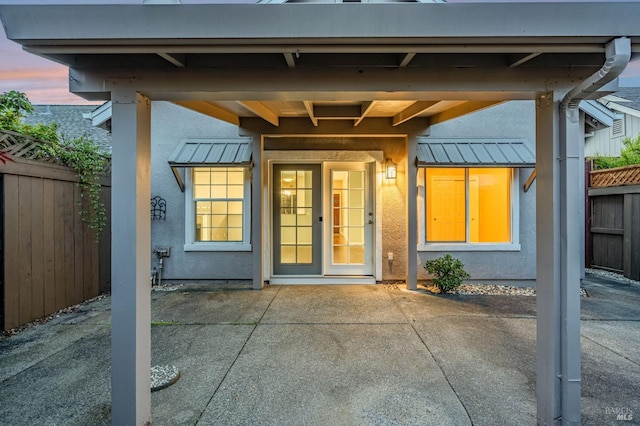 property entrance featuring a patio, stucco siding, and fence