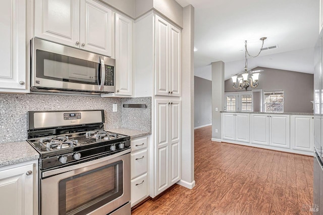 kitchen with an inviting chandelier, white cabinetry, vaulted ceiling, visible vents, and appliances with stainless steel finishes