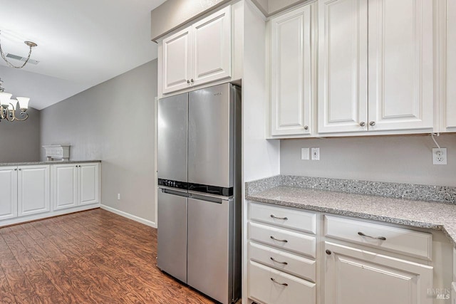 kitchen featuring freestanding refrigerator, an inviting chandelier, dark wood finished floors, white cabinetry, and baseboards