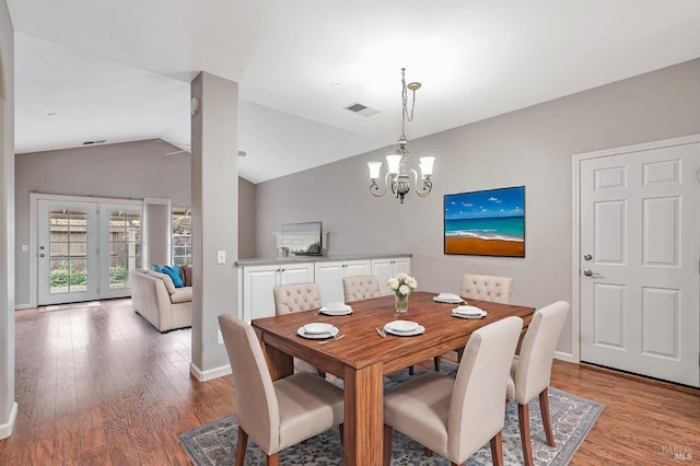 dining space featuring baseboards, a chandelier, light wood-style floors, visible vents, and lofted ceiling