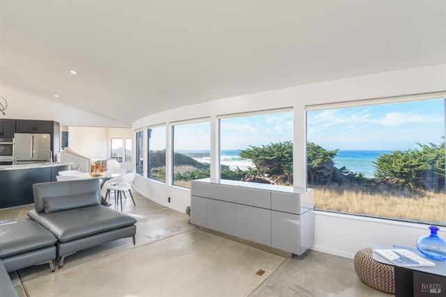 sunroom / solarium featuring a water view, concrete floors, baseboards, and lofted ceiling